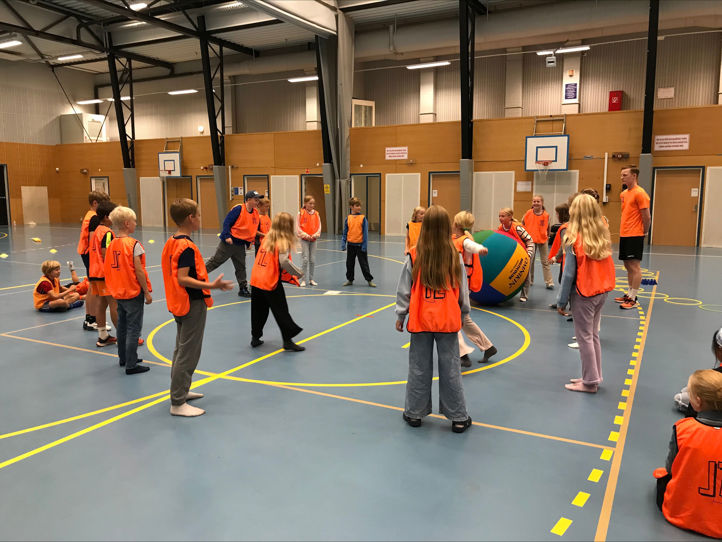 En gruppe mennesker i oransje vester i et treningsstudio